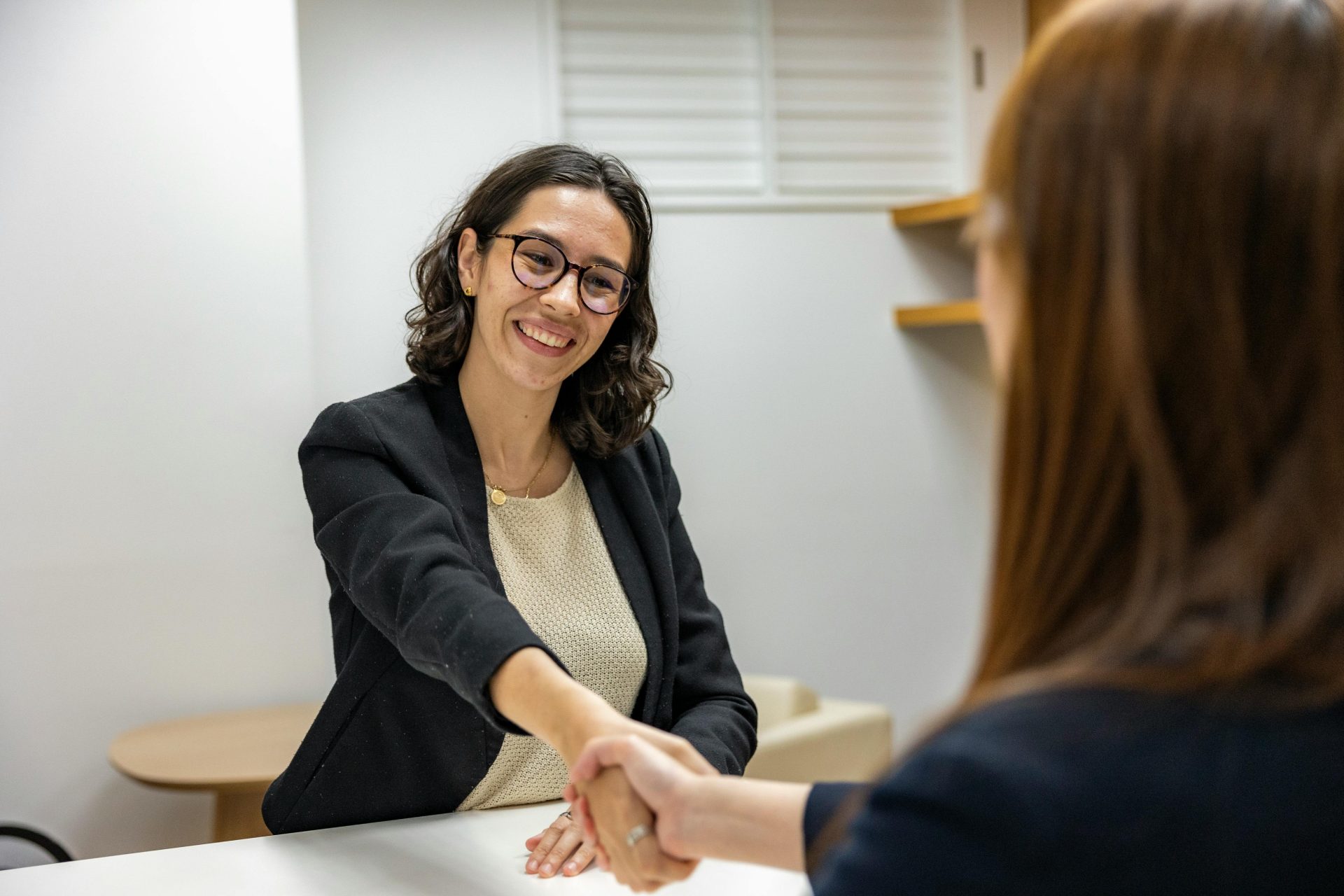 Geschäftsfrauen schütteln sich in einem Büro die Hände – ein Symbol für ein erfolgreiches Vorstellungsgespräch oder eine erfolgreiche Partnerschaft.